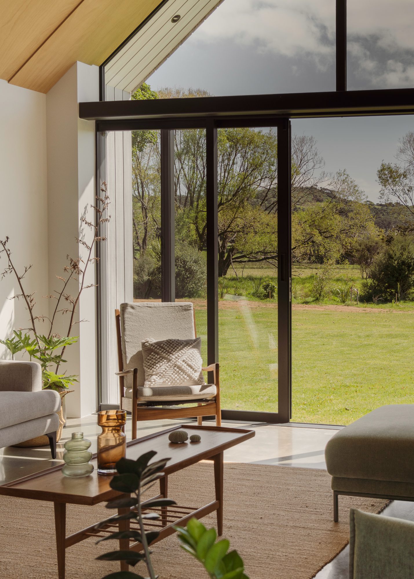 Awa Coastal armchair by full-height glazing with garden view, Whangapoua interior photography NZ