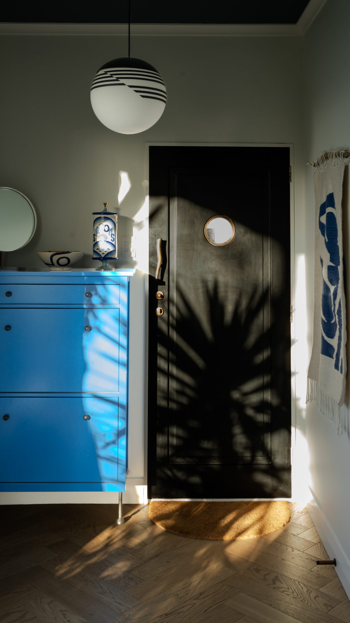 Seatoun House entry with black door and blue cabinet in raking light, Wellington interior photography NZ